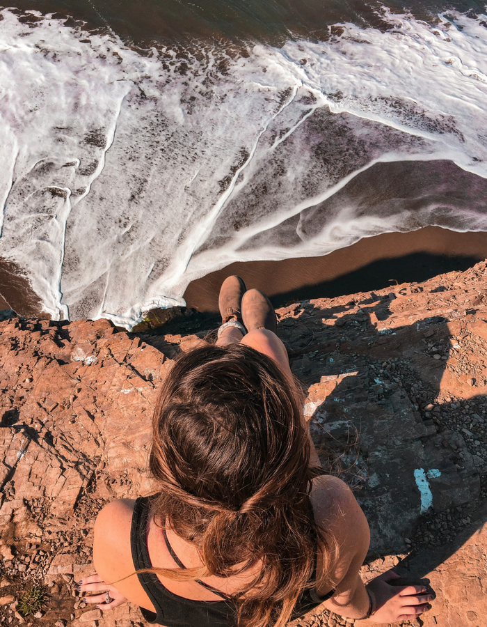 Sitting on the edge at the top of Alamere Falls, looking down at the waves rolling in