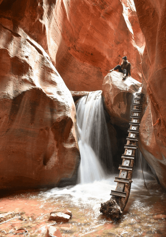 Sitting ontop of the iconic rock at the first waterfall on the Kanarra Falls trail