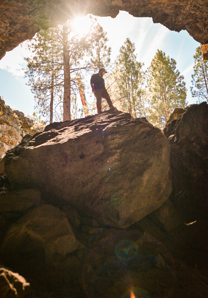 Francis climbing over the caves biggest boulder at Hidden Forest Cave